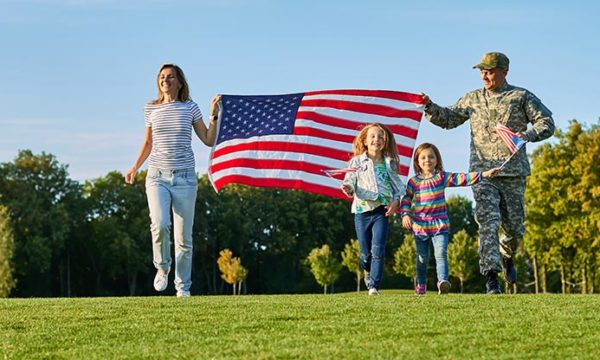military family holding American flag across park
