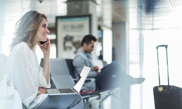 woman waiting for flight and talking to work at home agent