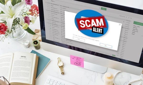 desktop computer with a scam alert sign