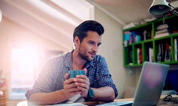 man working from home using laptop to look for jobs