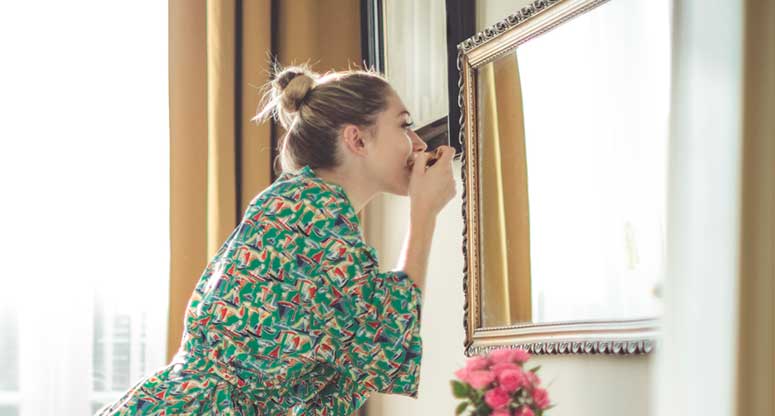 woman looking at her self in the mirror getting ready to go to work from home