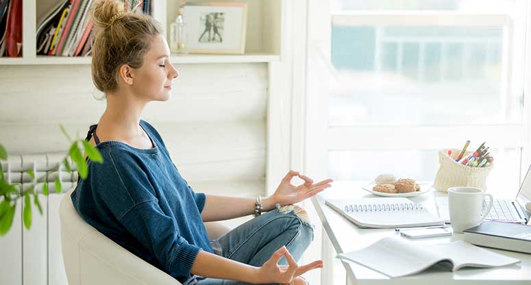 woman meditating while she works from home
