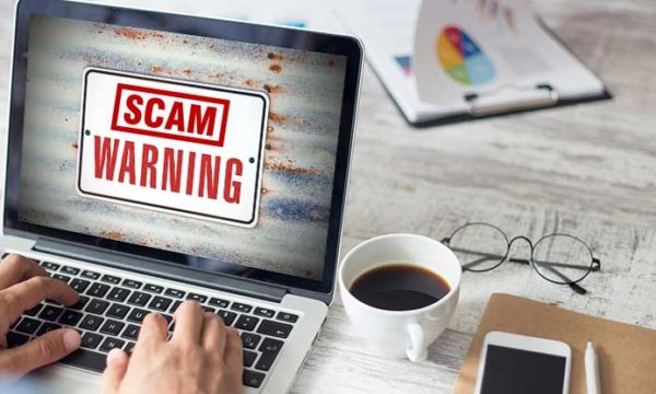 laptop screen with scam warning for working at home