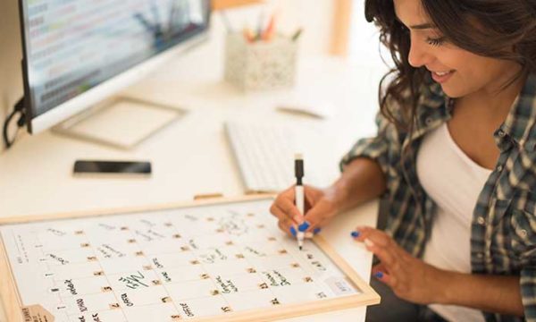 woman working from home writing on whiteboard calendar job