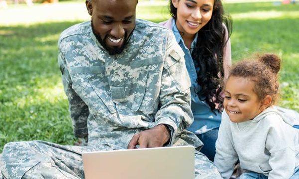 soldier spending time with family while checking computer work at home jobs