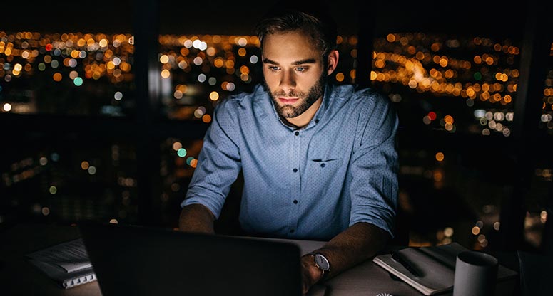 man looking at computer at night working from home best practices and benefits