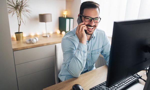 man talking on the phone and looking at computer screen showing the best work at home job