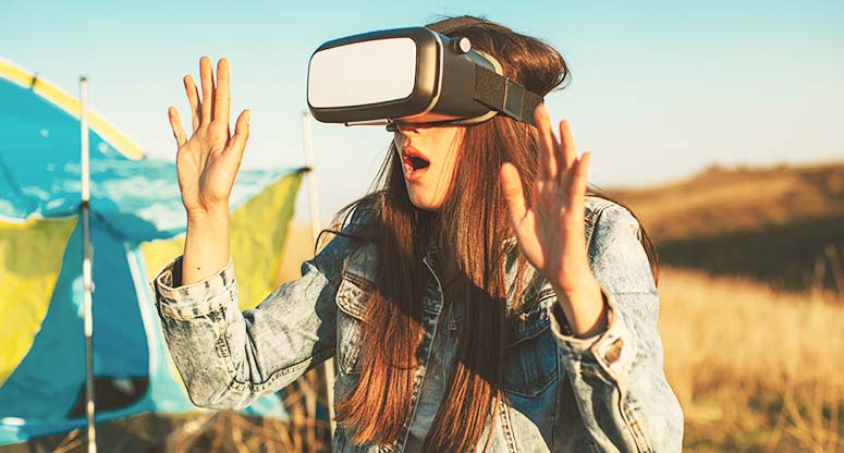 Girl with VR headset on with a virtual camp and tent as background