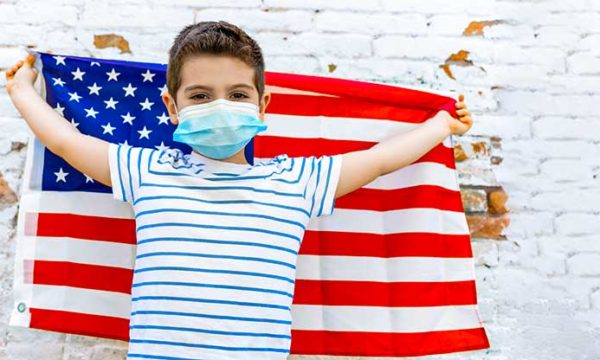 little boy holding an American flag with a mask