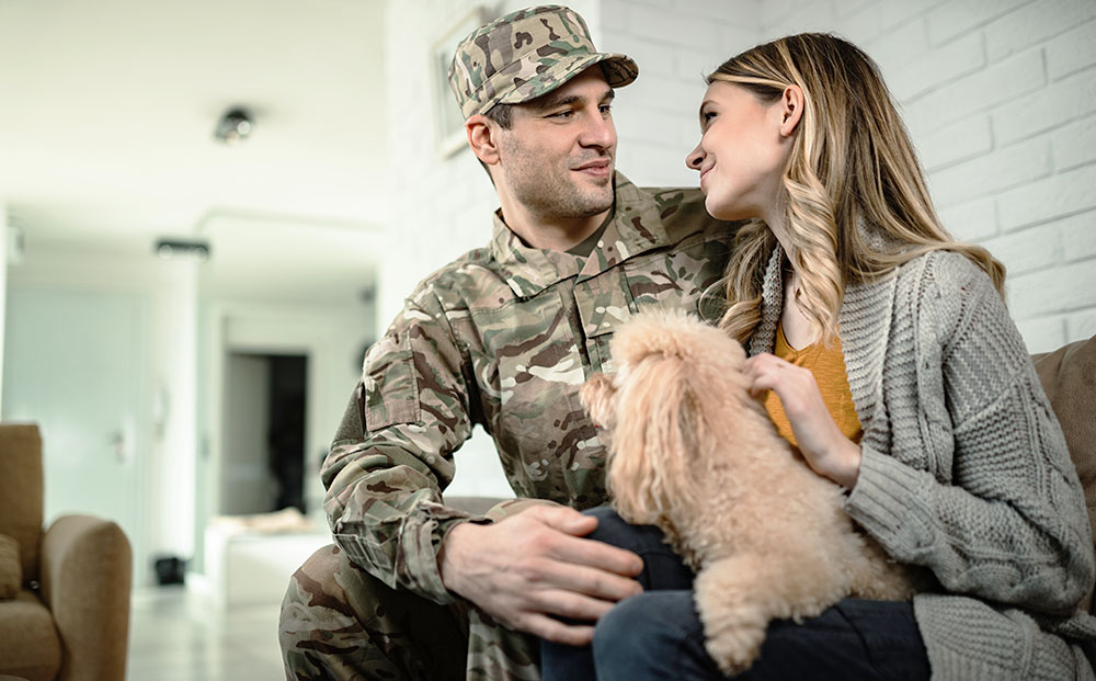 Military husband and spouse share a moment together with their dog