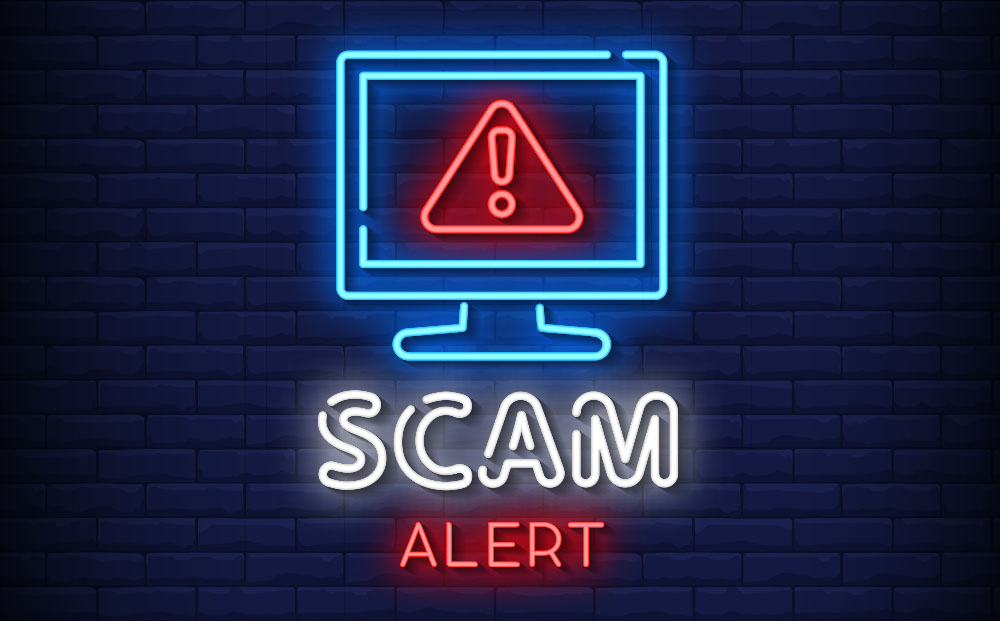 Illustration of neon lights in the shape of a computer monitor with a red error sign and the words Scam Alert written below it in neon lights