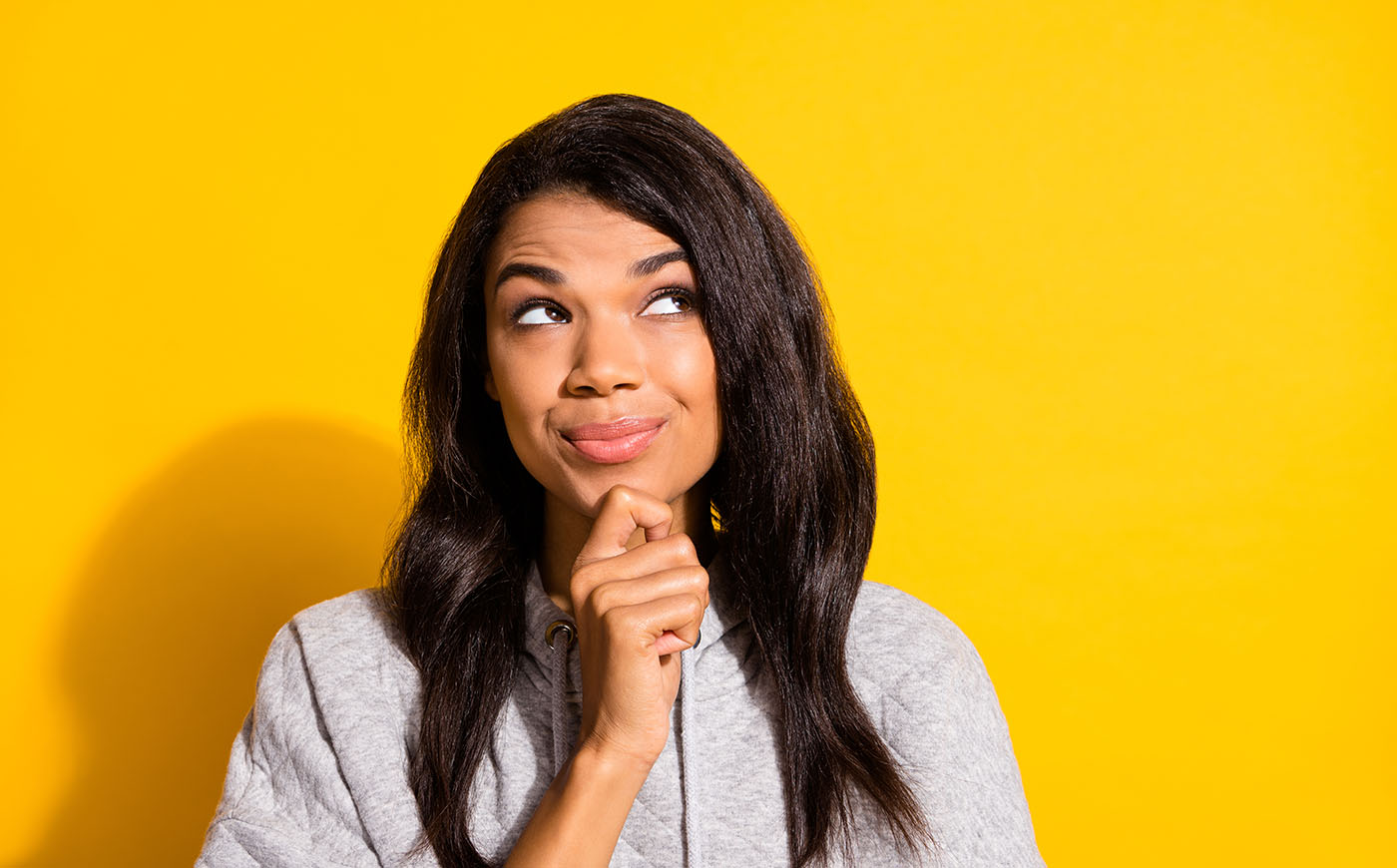 Black woman looking curiously upward in front of a yellow background
