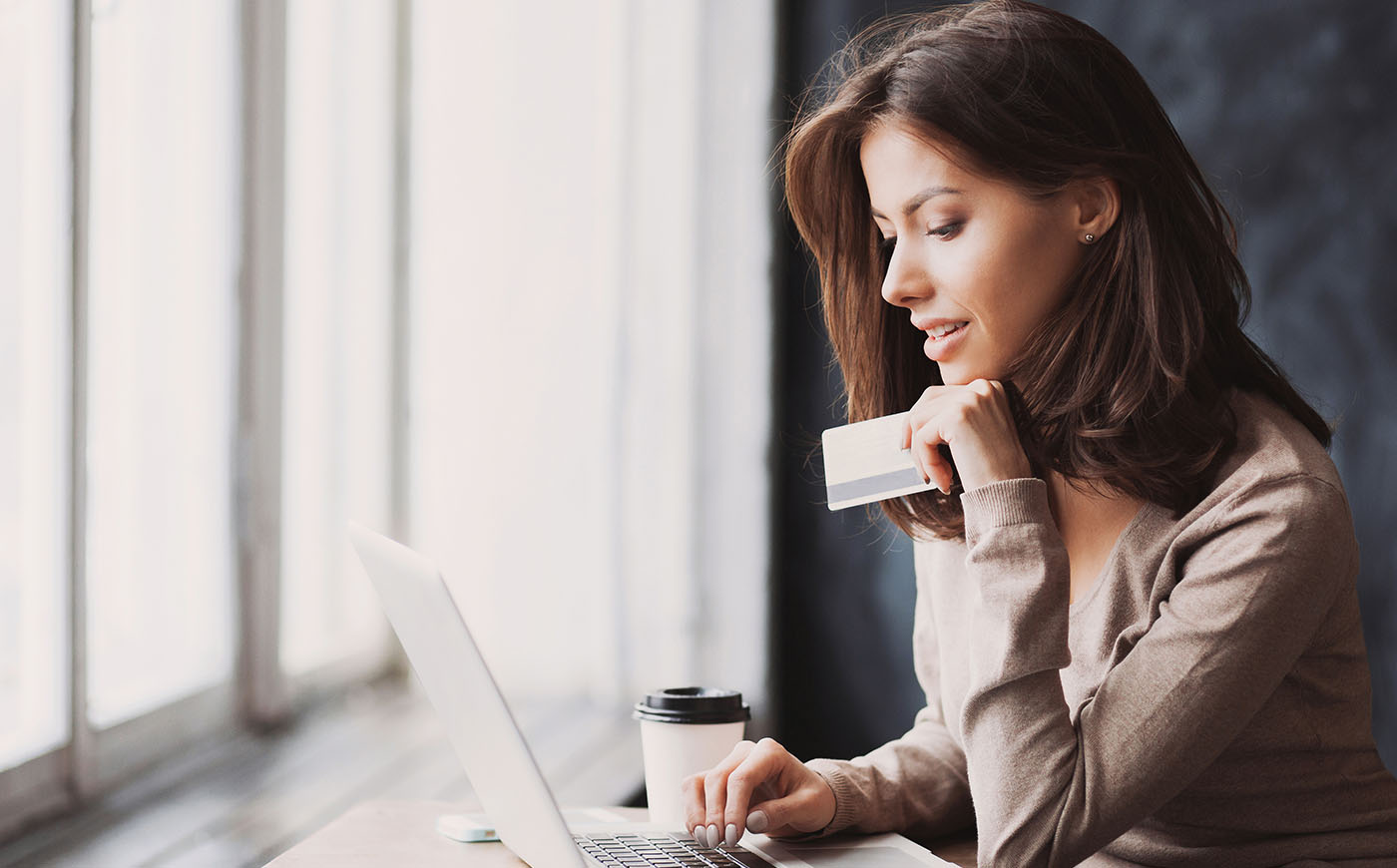Woman holding credit card and using laptop computer
