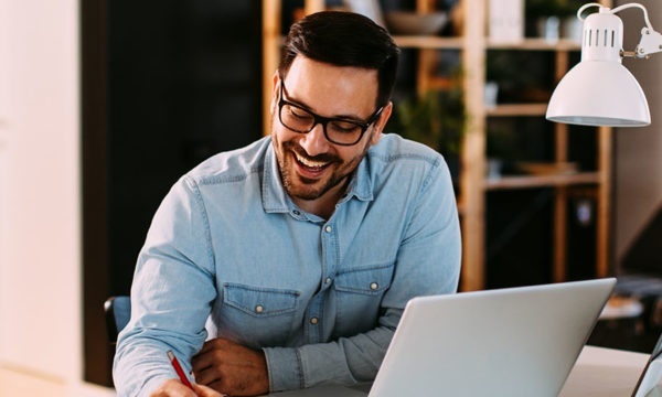 Young business man working at home with laptop and papers on desk