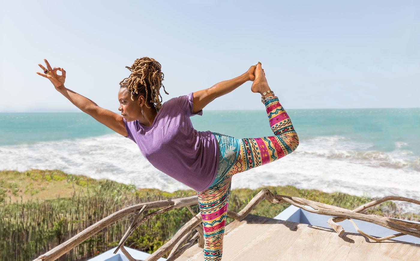 Black woman concentrates on a yoga pose on the beach