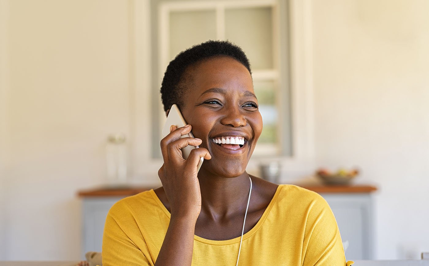 Smiling laughing Black woman talking on the phone in her home