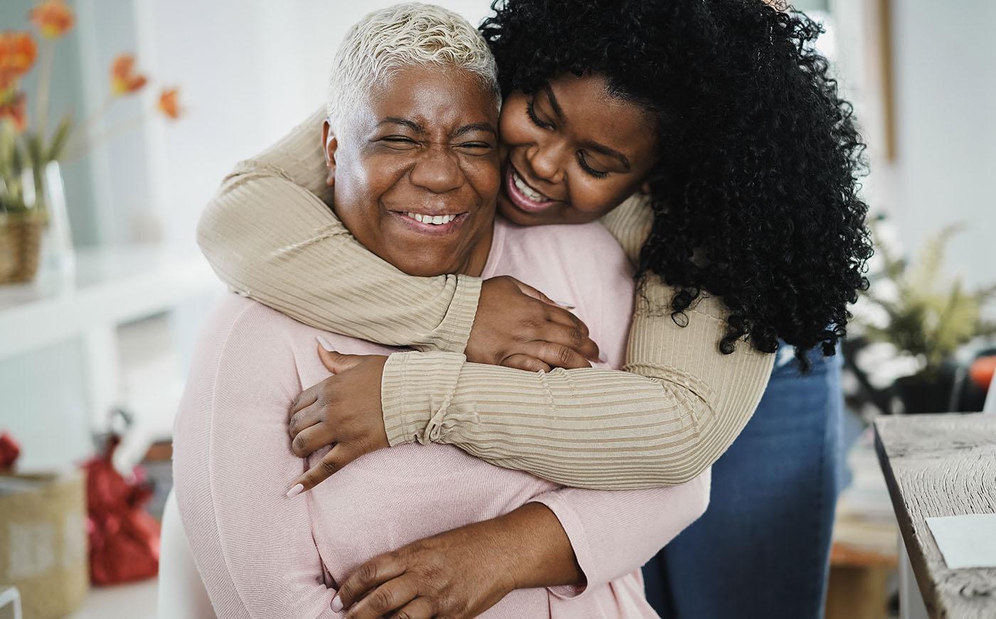 Black daughter hugging her mom indoors at home