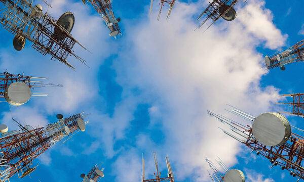 Straight-up shot from the ground of mobile phone communication towers reaching towards the sky above.