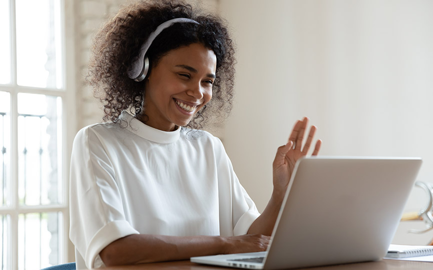 Young Black consultant smiles as she has conversation at home on her laptop