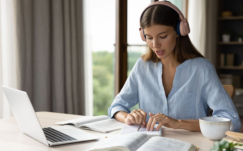 Customer service agent in her home office environment studies her notes as she responds to the customer in French