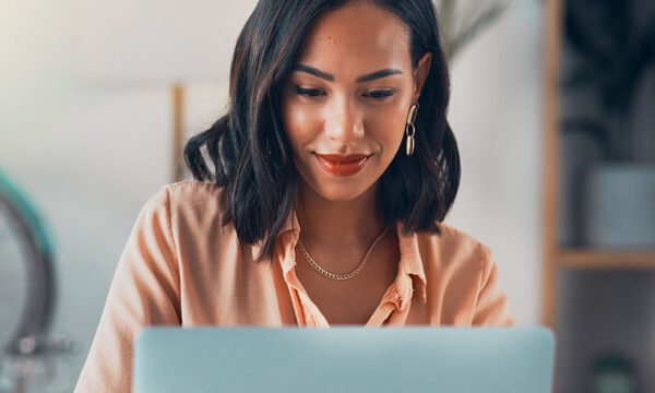 Competent woman smiles confidently at her computer as she applies for a remote job online