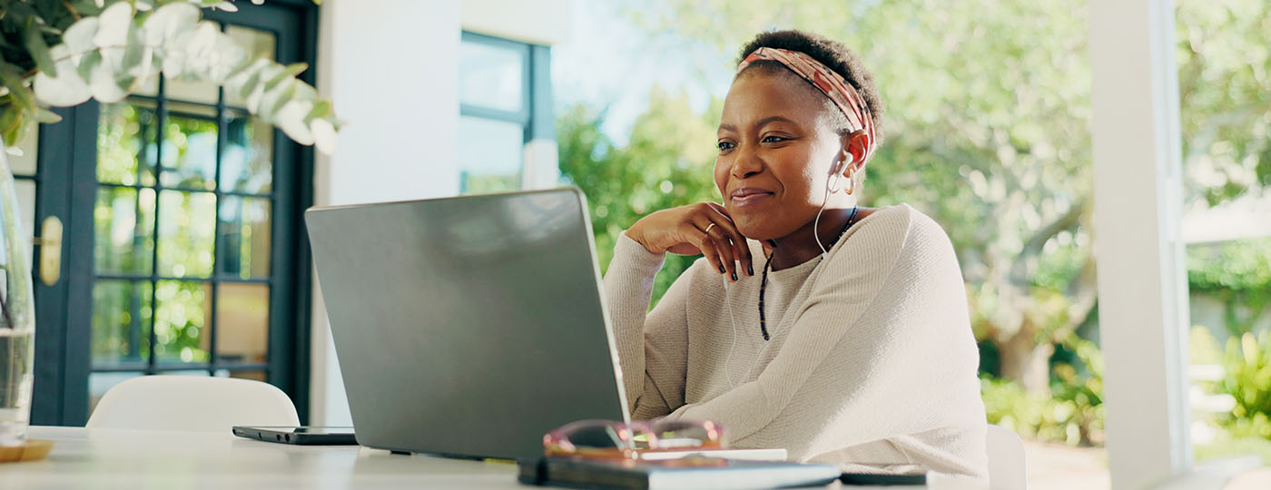 Intelligent and thriving mature woman smiles at her laptop as she researches tools to get her far in her work.