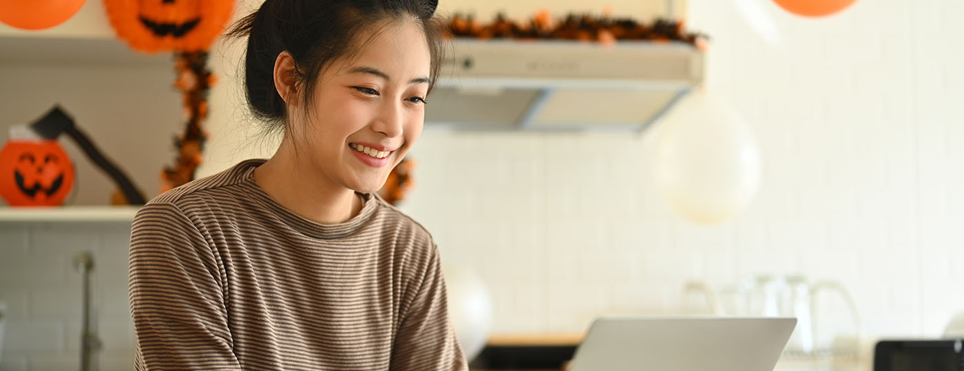 Smiling woman works on her laptop in a fall-decorated kitchen