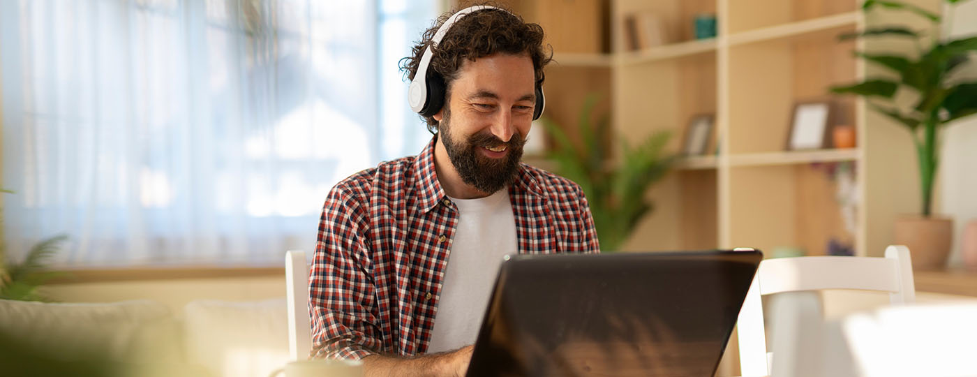 Young professional graduate male smiles at his laptop as he answers a phone call as an agent representative