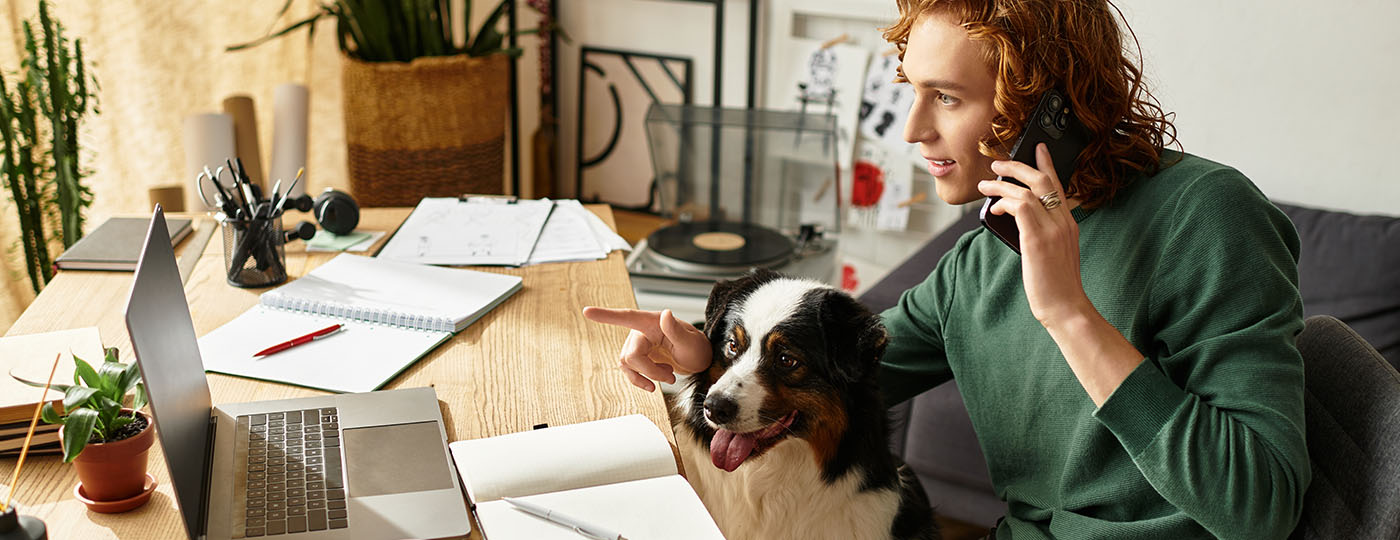 Cozy atmosphere of a young man working from home with his dog by his side, engaged in conversation