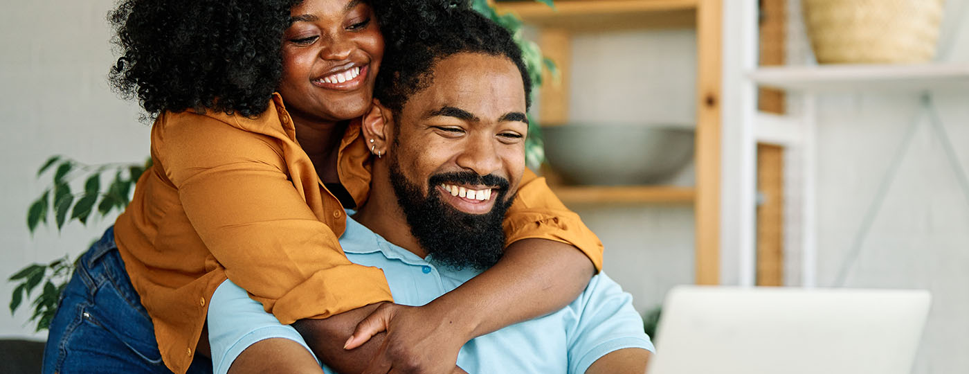 Young happy black couple having fun using a laptop at home