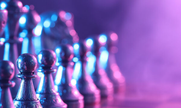 Chess pieces on checkerboard in color light, selective focus